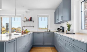 Una cocina moderna con gabinetes grises, una isla grande y vistas al exterior.