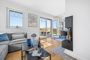 Una sala de estar moderna con un sofá, una chimenea y ventanas amplias.