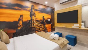 A hotel room with a large bed, a flat-screen TV, a wall-mounted air conditioner, and a mural of a mosque. - RV Grand (Hyderabad)