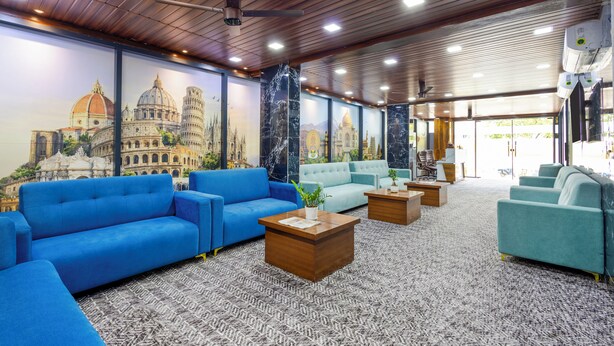 A lobby with blue sofas, a wooden ceiling, and a large mural of a famous building. - RV Grand (Hyderabad)