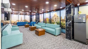 A room with a large sofa set, a refrigerator, and a wall with a mural of a famous building. - RV Grand (Hyderabad)