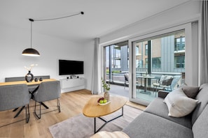A modern living room with a sofa, coffee table, and dining area. - The View C08 Hygge am Deich – Garden Furniture, Parasol, Shared Sauna, Parking (Dagebüll)