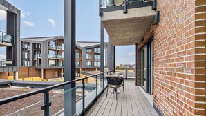 A modern building with a balcony, large windows, and a brick facade. - The View C08 Hygge am Deich – Garden Furniture, Parasol, Shared Sauna, Parking (Dagebüll)