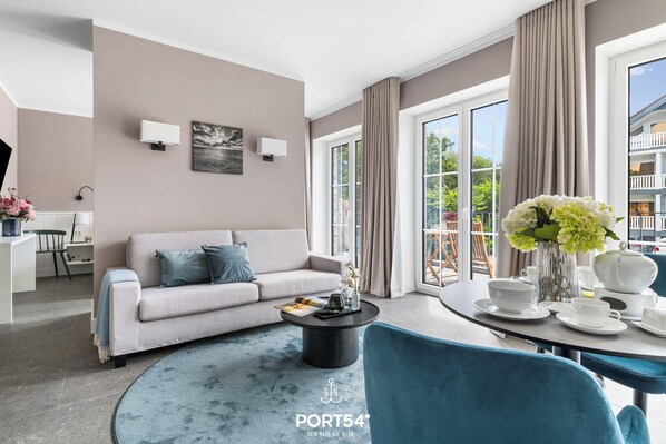 A modern living room with a sofa, coffee table, and dining table set. - The View C08 Hygge am Deich – Garden Furniture, Parasol, Shared Sauna, Parking (Dagebüll)