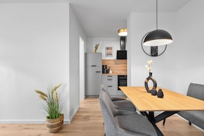 A modern kitchen with grey cabinets, a wooden countertop, and a black hanging light fixture. - The View C08 Hygge am Deich – Garden Furniture, Parasol, Shared Sauna, Parking (Dagebüll)