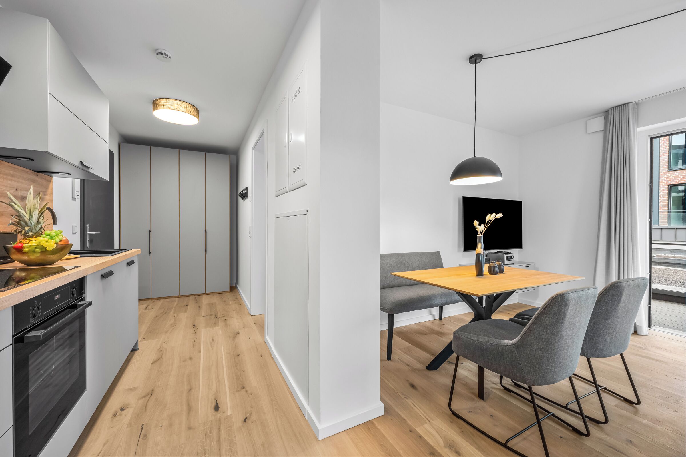 Eine moderne Küche mit Holztischplatte, integriertem Backofen und einem Essbereich mit Tisch und Stühlen.