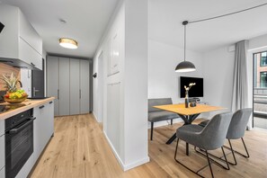A modern kitchen with a wooden countertop, a built-in oven, and a dining area with a table and chairs. - The View C08 Hygge am Deich – Garden Furniture, Parasol, Shared Sauna, Parking (Dagebüll)