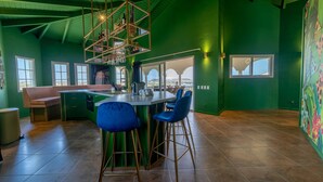 A modern kitchen with a central island, bar stools, and a view through large windows. - The View The Ambassador (Jan Thiel)