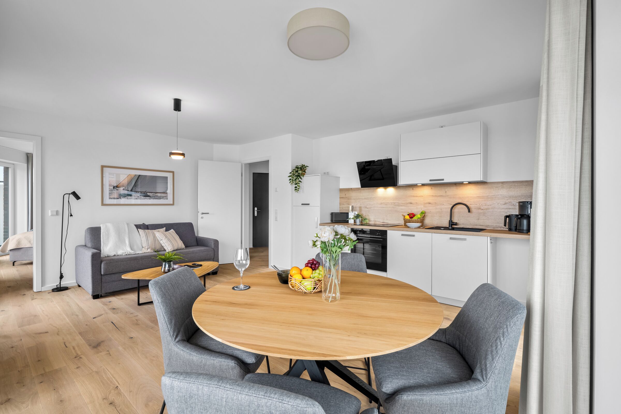 Een moderne keuken met witte kasten, een houten aanrecht en een zwarte afzuigkap.