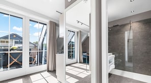 Ein modernes Interieur mit großen Fenstern, einem Balkon und einer Duschkabine.