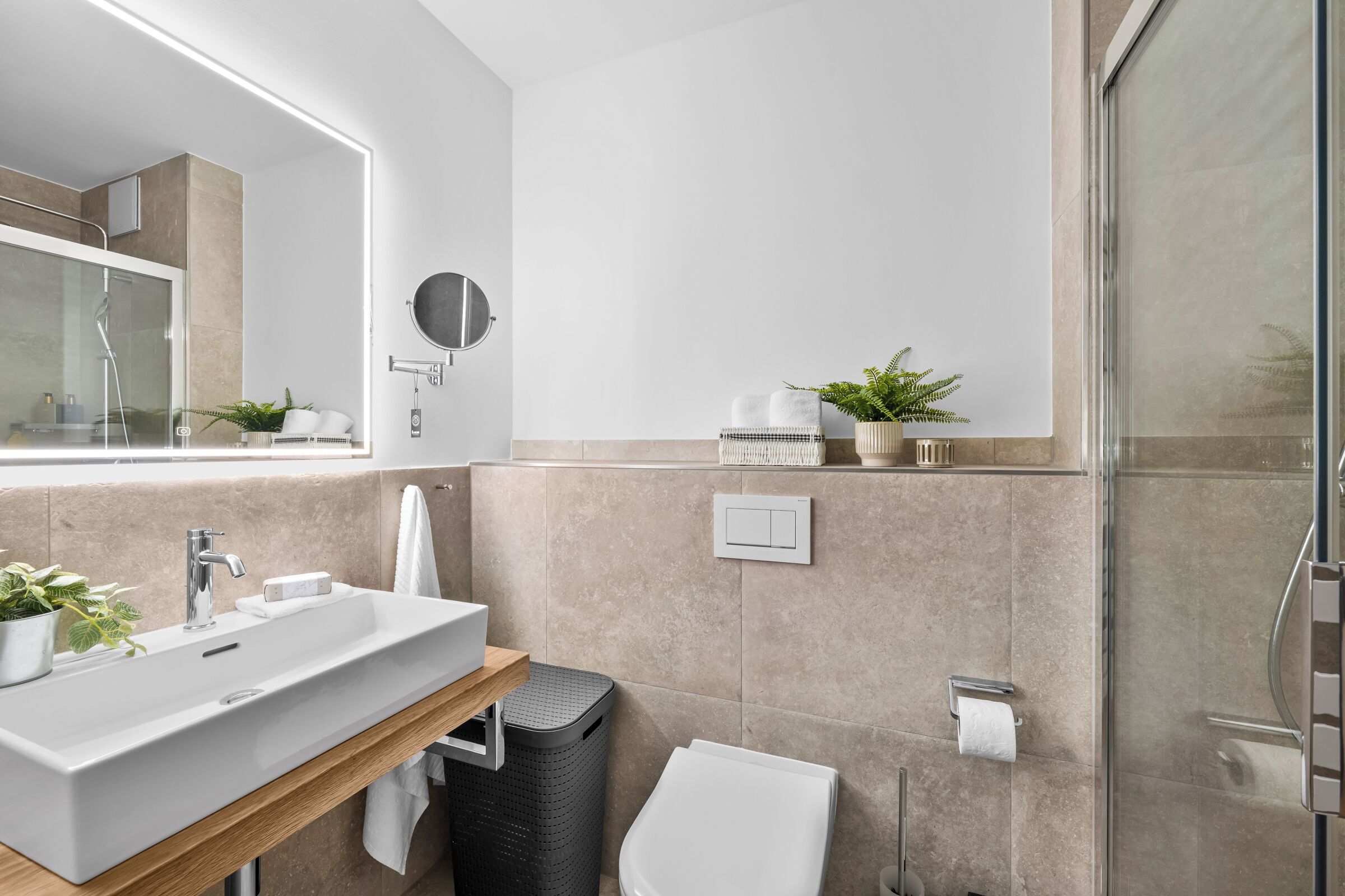 A modern bathroom with a large sink, mirror, and shower.