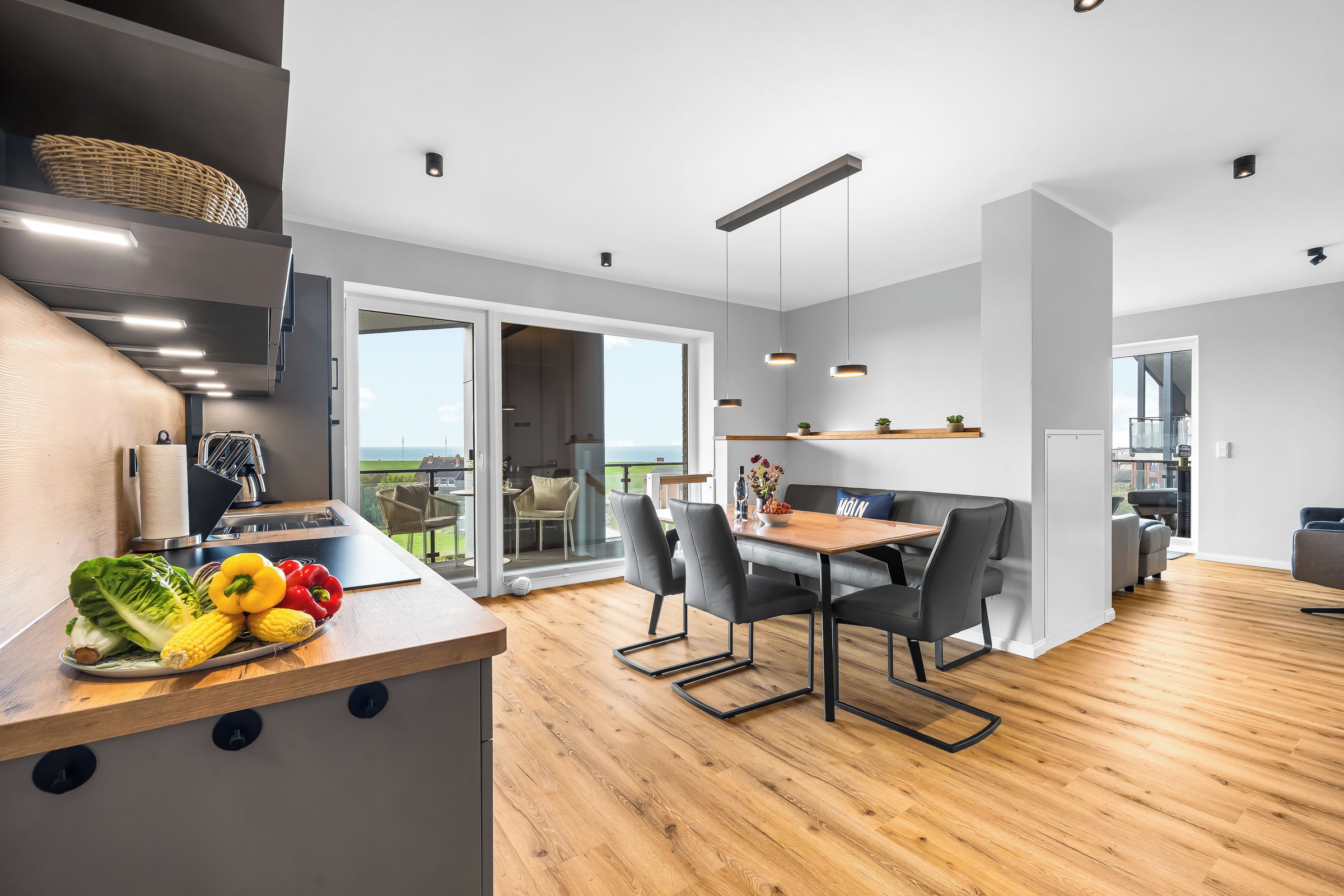 A modern kitchen with a wooden countertop, a dining area with a table and chairs, and a view of the outdoors.