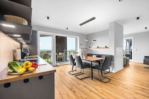 A modern kitchen with a wooden countertop, a dining area with a table and chairs, and a view of the outdoors. - The View C11 Nordseeblick - Sea view, sauna, grill (Dagebüll)