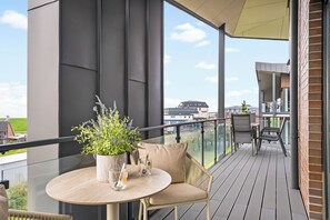 A balcony with a round table, two chairs, a potted plant, and a glass. - The View C11 Nordseeblick - Sea view, sauna, grill (Dagebüll)