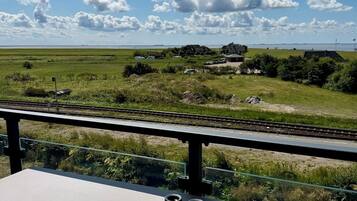 Una mesa con unos binoculares, con vistas a un paisaje pintoresco y un cielo despejado, con un horizonte lejano.