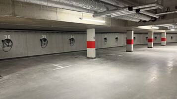 Un estacionamiento subterráneo con pilares de concreto, espacios numerados y luces en el techo.