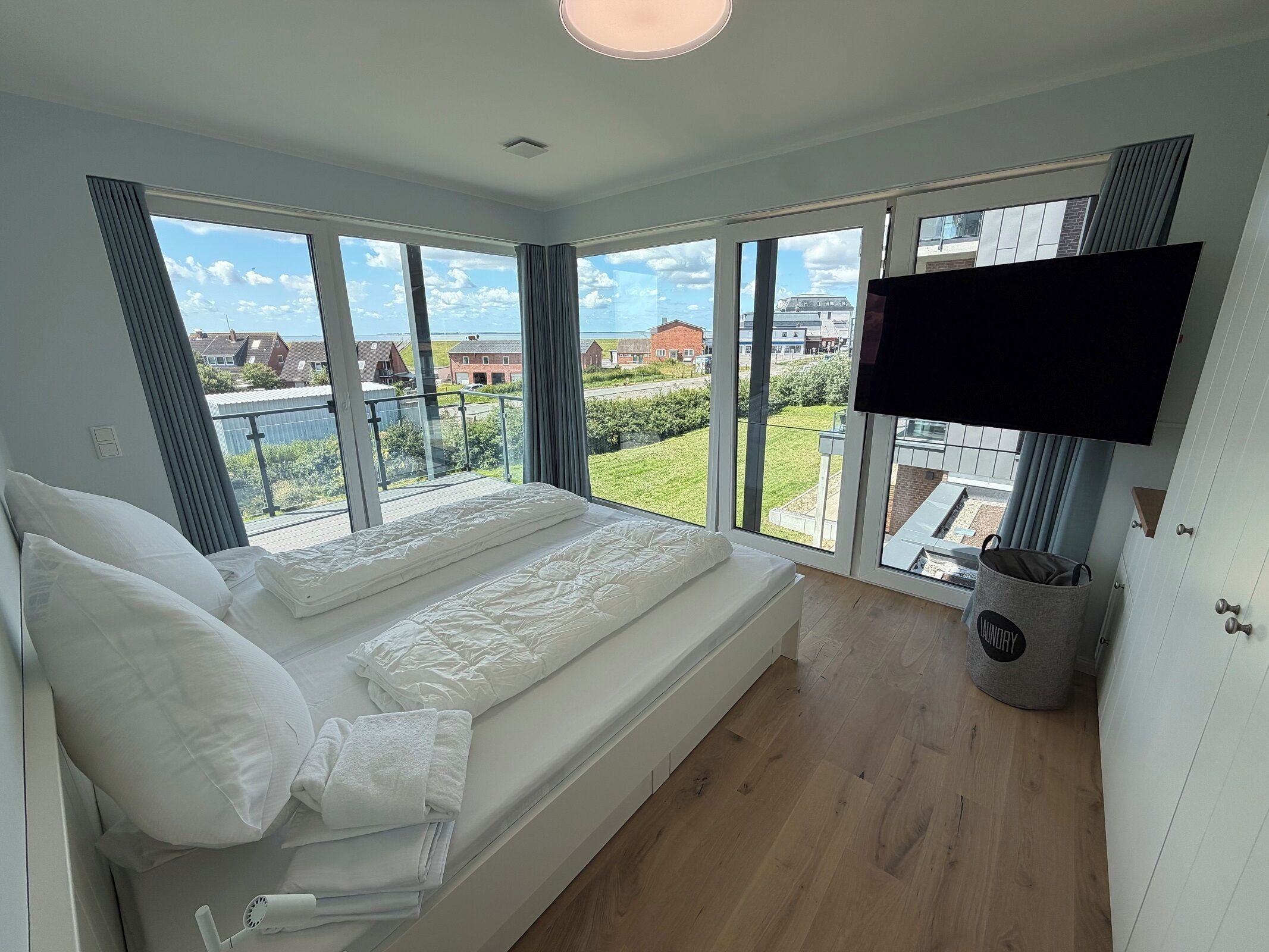 Un dormitorio con una cama grande, un televisor montado en la pared y vistas al exterior.