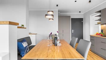 A modern dining area with a wooden table, grey chairs, and pendant lighting.