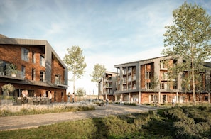 A modern residential building with brick facades, balconies, and a paved courtyard with greenery. - The View C09 Ankerplatz - Sea view,sauna,maisonette apartment, EV station (Dagebüll)