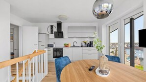 Een moderne keuken met witte kasten, een inbouwoven en een groot raam met uitzicht op de stad.