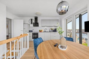 Eine moderne Küche mit weißen Schränken, einem eingebauten Ofen und einem großen Fenster mit Blick auf die Stadt.