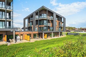 Ein modernes mehrstöckiges Gebäude mit Balkonen, großen Fenstern und einem Flachdach.