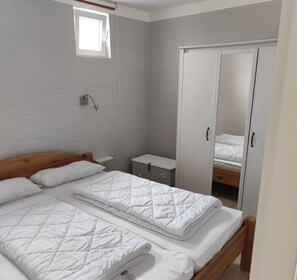 A bedroom with two beds, a wardrobe, a small bedside table, and a window. - ERNST vacation home close to the Frisian beach in Tossens for the whole family (Butjadingen-Tossens)