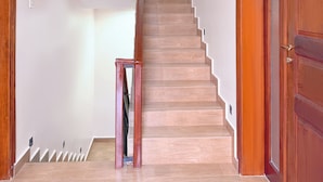 A staircase with wooden steps and a handrail, leading to a landing with a door. - Constatia Homes Bunga (Kampala)