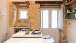 Een kleine keuken met een stenen muur, een raam en een houten plank met boeken.