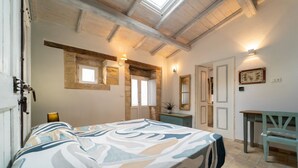Een slaapkamer met een bed, een bureau, een stoel, een raam en een deur.