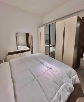 Ein Schlafzimmer mit einem großen Bett, einem Kleiderschrank, einem Spiegel und einem Nachttisch.