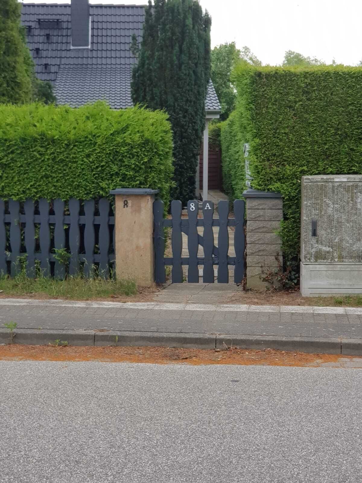 A residential area with a gated entrance, a mailbox, and a hedge.