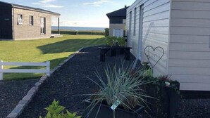 A modern building with a gravel pathway, potted plants, and a white fence. - 4 Star Holiday Home in Juelsminde (Juelsminde)