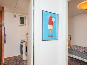 A room with a bed, a washing machine, and a poster on the wall. - 4 Person Holiday Home in Grenaa (Grenaa)