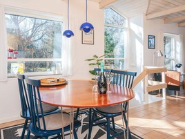 Un comedor con una mesa redonda de madera, sillas azules y una botella de vino.
