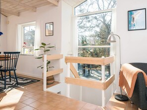 A room with a wooden bunk bed, a dining table with chairs, a large window with a view of trees, and a lamp. - 4 Person Holiday Home in Grenaa (Grenaa)