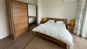 A bedroom with a bed, a wardrobe, a mirror, a bedside table, and an air conditioning unit. - City Apartment With Terrace (Hasselt)
