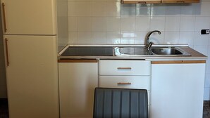 Eine kleine Küche mit Kühlschrank, Spüle, Geschirrspüler und einem Esstisch.