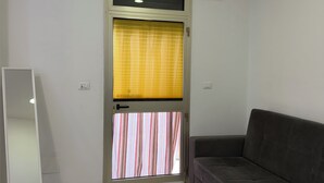Ein Zimmer mit Tür, einer Couch und einem Spiegel.