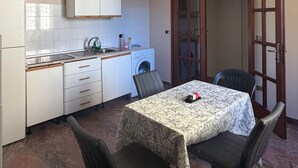 Eine kompakte Küche mit Essbereich, einer Waschmaschine und einem Tisch mit Stühlen.