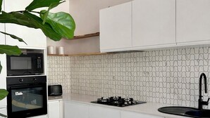 A modern kitchen with white cabinets, a microwave, oven, and a gas stove. - Brand New 2x2 Escape | Relax & Unwind (Herron)