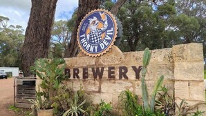 A sign for Thorny Devil Brewery with a logo, surrounded by potted plants and trees. - Brand New 2x2 Escape | Relax & Unwind (Herron)
