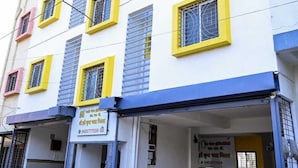 Ein mehrstöckiges Gebäude mit weißer Fassade, gelben Fensterrahmen und blauen Akzenten.