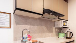 A kitchen with a microwave, kettle, and coffee maker. There is a framed document on the wall. - Peaceful 2-bedroom condo in wonderful Baguio getaway (Baguio)