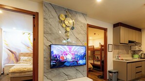 A modern kitchen with a TV, marble backsplash, and wooden cabinets. - Peaceful 2-bedroom condo in wonderful Baguio getaway (Baguio)