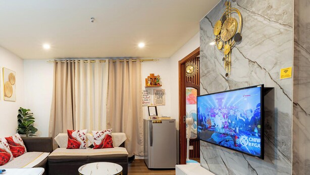 A modern living room with a sofa, a TV, a small table, and a decorative wall piece. - Peaceful 2-bedroom condo in wonderful Baguio getaway (Baguio)