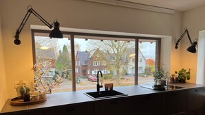 A modern kitchen with a large window, a sink, and two pendant lights. - Stylish Apartment in Bree Centre (Bree)