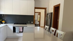 A modern kitchen with white cabinets, a central island, and a dining table with chairs.