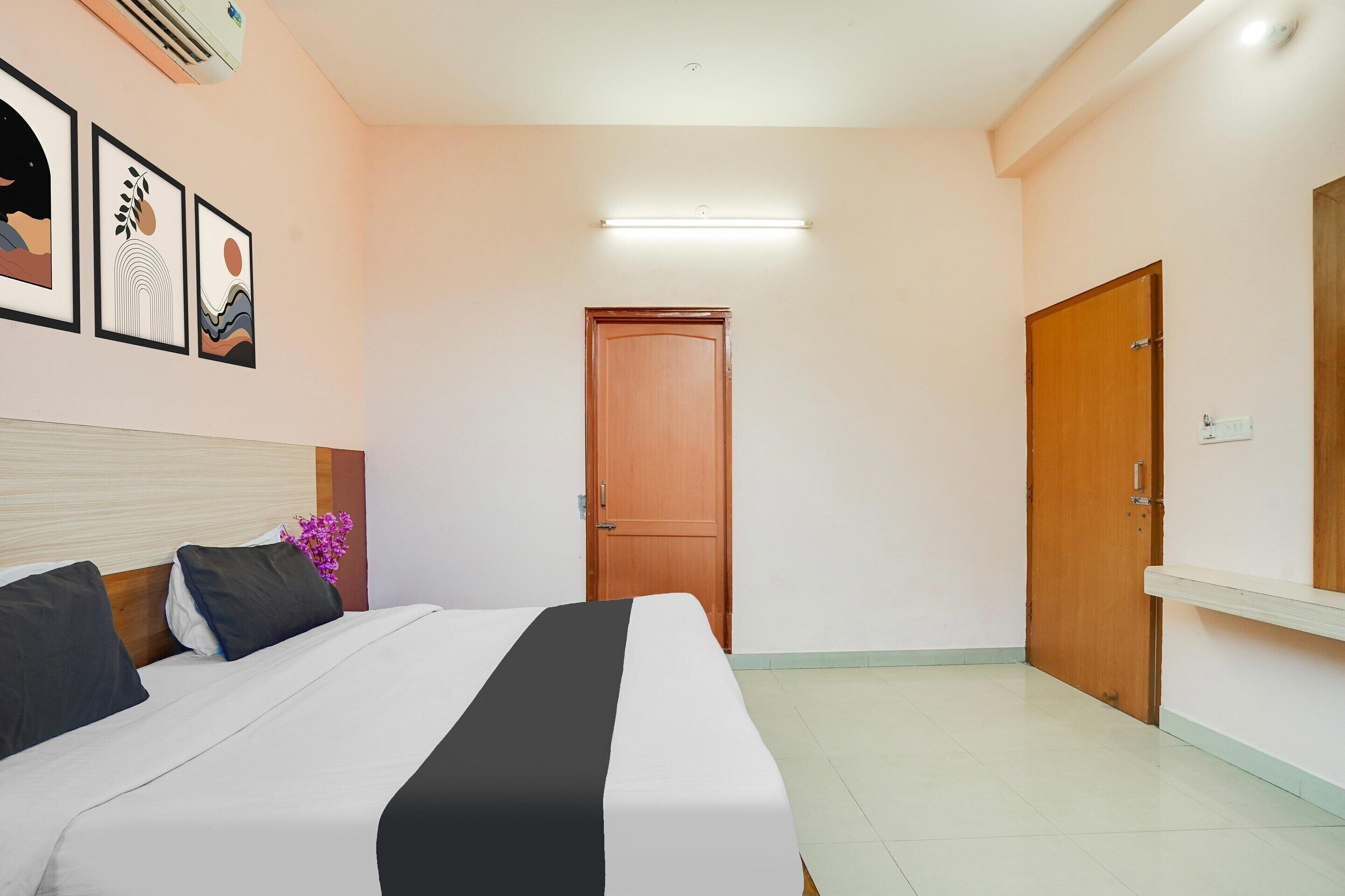 Una camera da letto con un letto, una porta in legno, un condizionatore d'aria a muro e opere d'arte incorniciate.