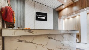 Bancada de receção com tampo de mármore, placa a indicar que se trata de um townhouse com serviços de empresa, e interior em madeira.